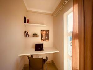 a room with a desk with a laptop and a window at Biz & Bliss Work & Serene Views in Windhoek