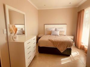 a bedroom with a bed with a dresser and a mirror at Biz & Bliss Work & Serene Views in Windhoek