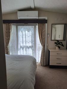 a bedroom with a bed and a large window at Lodge at Billing Aquadrome Holiday Village in Great Billing