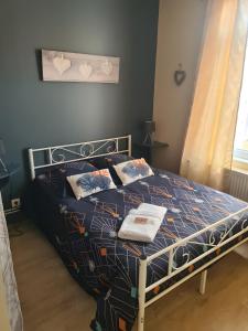 a bedroom with a bed with a blue comforter and pillows at La Jolythalys bord de mer 300m in Étaples