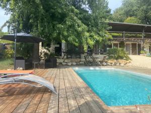 a swimming pool on a wooden deck with an umbrella at Dépendance atypique 2chbres parc piscine in Villebrumier