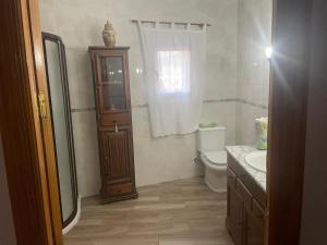 a bathroom with a toilet and a wooden cabinet at Hostal Casa López in La Zarza