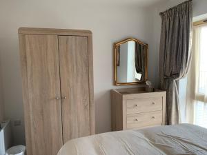 a bedroom with a dresser and a mirror at Bushmills Boutique Apartment in Bushmills