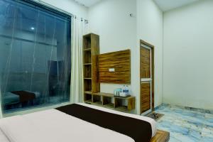 a bedroom with a bed and a large window at Hotel O The Suresh Mahal Resort in Jaipur