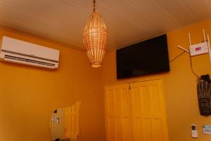 a room with a chandelier and a television and a door at Casinha Aconchegante em Alter do Chão 2min da ilha in Alter do Chao