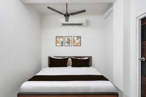 a bed in a white room with a ceiling fan at Hotel O Sushant Hotels NSEZ Metro Station in Sūrajpur