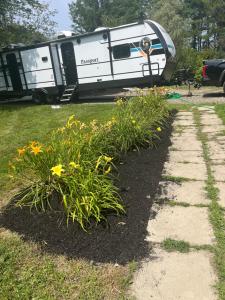 Ein Anhänger steht auf einem Feld mit Blumen in der Unterkunft Cozy camper escape close to boothbay in Edgecomb + 2 Fotos