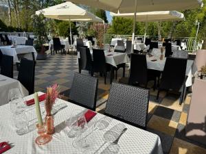 a restaurant with white tables and chairs and umbrellas at Hôtel l'Orée des Roches in Saales