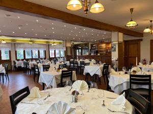 ein Esszimmer mit weißen Tischen und Stühlen in der Unterkunft Hôtel l'Orée des Roches in Saales