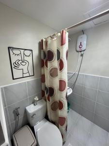 a bathroom with a toilet and a shower curtain at Stayease Studio in Lapu Lapu City +8 photos