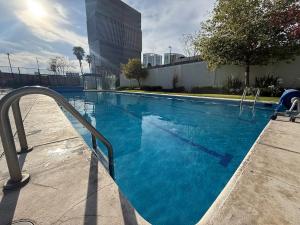 a swimming pool with blue water in a building at Exclusive Comfort Apartment in Querétaro