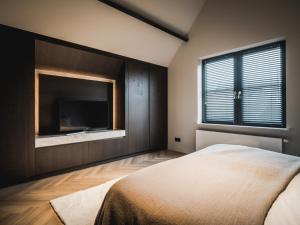 a bedroom with a large bed and a flat screen tv at Luxe Poolhouse Ouddorp in Ouddorp