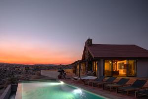 a villa with a swimming pool in the desert at sunset at Las Rocas By The Cohost Company in Yucca Valley