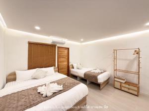 ein Hotelzimmer mit zwei Betten und einem Spiegel in der Unterkunft เมริโค่ บางแสน บีช Merico Bangsaen Beach in Ban Laem Thaen