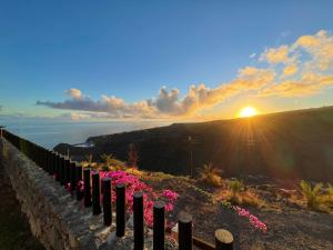 a fence with pink flowers in front of the sunset at Villa La Pintora in Playa de Santiago