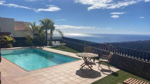 a swimming pool with a table and chairs and the ocean at Villa La Pintora in Playa de Santiago