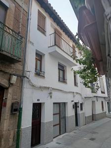 a white building with windows and balconies on a street at El Apartamento de Hervás in Hervás