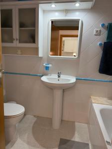 Un baño con lavabo, inodoro y espejo. en Sesimbra Village T1, en Sesimbra