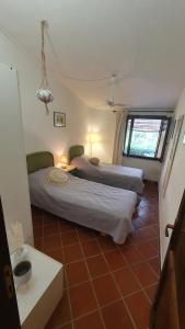 two beds in a room with a tiled floor at Bougainvilla in Costa Paradiso