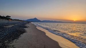 a beach with the sun setting over the water at a due passi dal mare in Campofelice di Roccella +7 photos