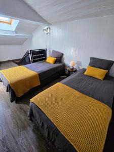 a room with two beds with yellow blankets at La maison du père Bellessort in Régnié