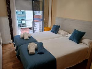 two beds in a hotel room with towels on them at Alojamiento Morriña in O Pedrouzo