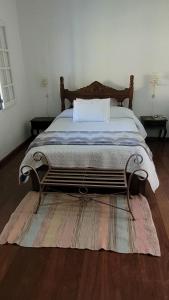 ein Schlafzimmer mit einem Bett und einem Teppich auf dem Boden in der Unterkunft Suítes da Rua Belica in Tiradentes