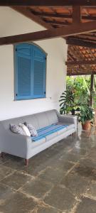 ein weißes Sofa auf einer Terrasse mit einem blauen Fenster in der Unterkunft Suítes da Rua Belica in Tiradentes