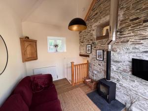 ein Wohnzimmer mit einer Steinmauer mit einem Holzofen in der Unterkunft Maristow Cottages, overlook Tamar Valley Dartmoor in Plymouth