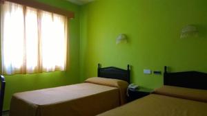 a green room with two beds and a window at Hostal Villa María in La Nava de Ricomalillo