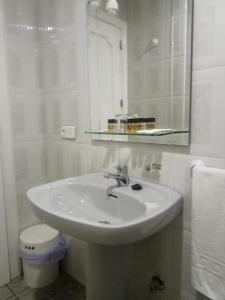 Un baño blanco con lavabo y espejo. en Hostal Villa María, en La Nava de Ricomalillo 9 fotos más