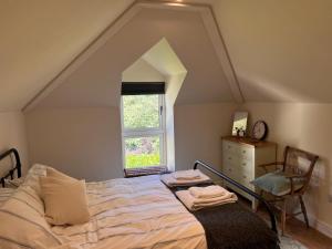 ein Schlafzimmer mit einem Bett, einem Fenster und einer Kommode in der Unterkunft Maristow Cottages, overlook Tamar Valley Dartmoor in Plymouth