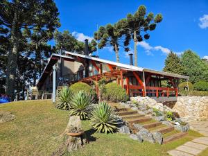 a house with a bunch of plants in front of it at Refúgio das Nuvens | by The Lodges in Campos do Jordão