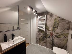 a bathroom with a sink and a mural on the wall at Suwałki Kościuszki Centrum in Suwałki