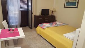 a small bedroom with a bed and a table and a tv at Apartments Grispolis in Tivat
