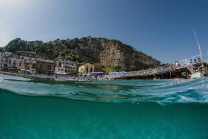 a boat in the water next to a pier at Hotel Baia Di Puolo in Massa Lubrense