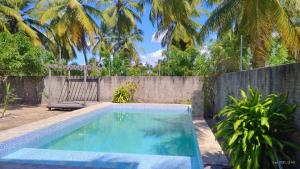 a swimming pool in a backyard with a fence and palm trees at Refugio Kitesurf - ilha do Guajirú in Itarema