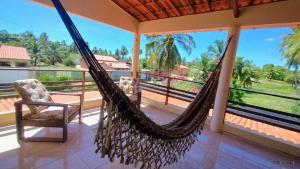 a hammock on a porch with a chair and a view at Refugio Kitesurf - ilha do Guajirú in Itarema