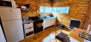 a kitchen in a log cabin with a refrigerator at Cabaña Villa Ventana - Chingolo Bosque in Villa Ventana