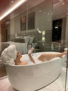 a woman laying in a bath tub in a bathroom at Hotel 4WOO in Telêmaco Borba
