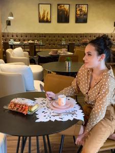 a woman sitting at a table with a plate of food at Hotel 4WOO in Telêmaco Borba