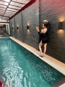 a woman standing next to a swimming pool at Hotel 4WOO in Telêmaco Borba