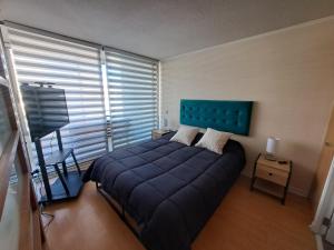 une chambre avec un lit bleu et une fenêtre dans l'établissement Depto central 2, à Viña del Mar