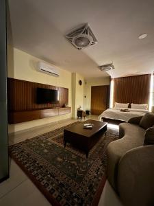 a bedroom with a bed and a couch and a tv at SkyLuxe Studio 2 with rooftop Pool & Self Check In in Islamabad