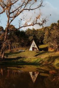 a barn in a field next to a body of water at Cabana com banheira in Gramado