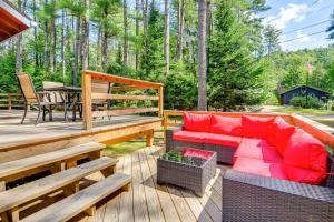 a patio with a red couch on a wooden deck at Forested Retreat with Sauna 5 Mi to Schroon Lake in Schroon Lake