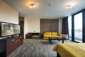 a hotel room with a television and a yellow couch at Hotel Panorama in Štrbské Pleso