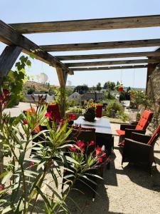 a patio with a table and chairs and flowers at Ferienwohnung im Chaletstil Sonnenidyll 51 qm Wellness Fitness Sauna Bergrödelhof in Feilitzsch