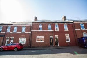 a red brick building with a red car parked in front at Vacant Nests The Fredrick Close To Sea Front in Seaham