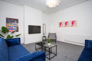 a living room with a blue couch and a tv at Vacant Nests The Fredrick Close To Sea Front in Seaham